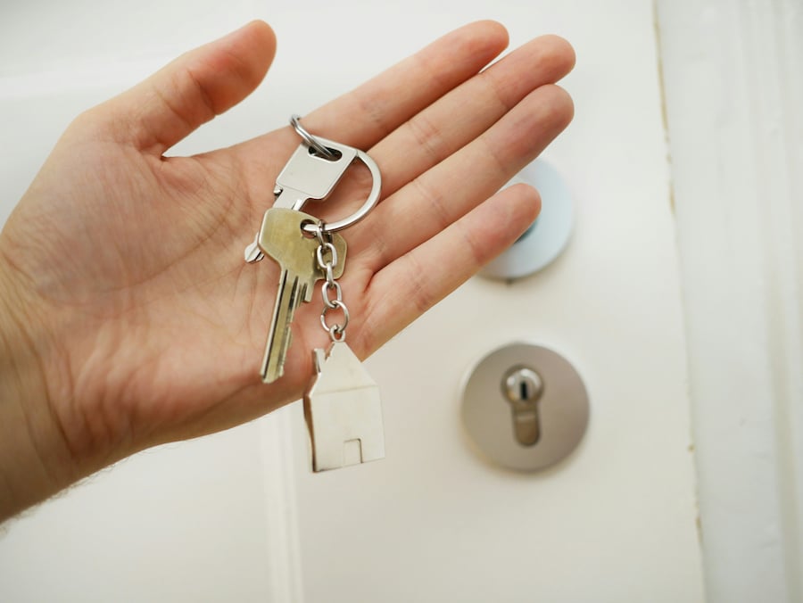real-estate - Johnston & Zagurskie PC Hand holding keys ready to unlock a door, symbolizing a real estate closing and successful property ownership transfer.